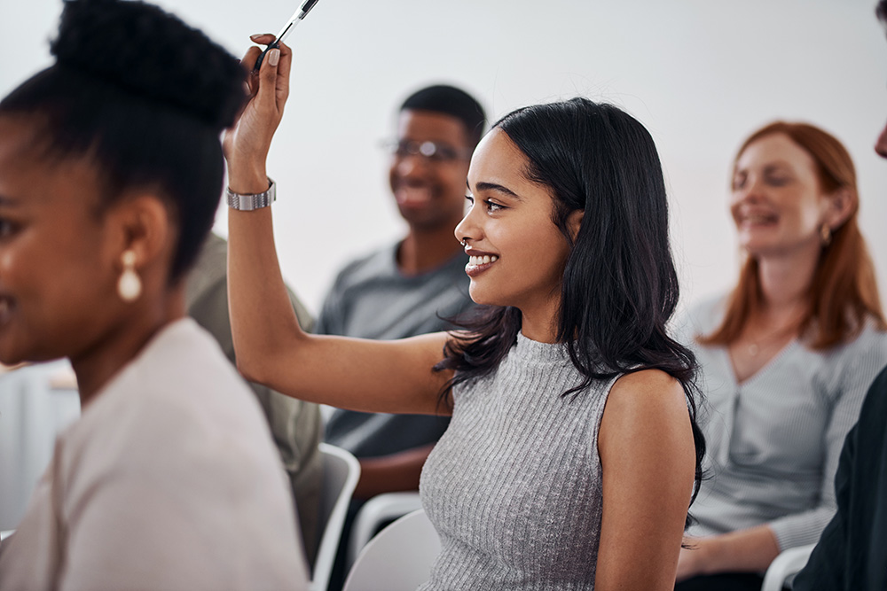 I have a quick question. Shot of a young businesswoman raising her hand during a conference.
